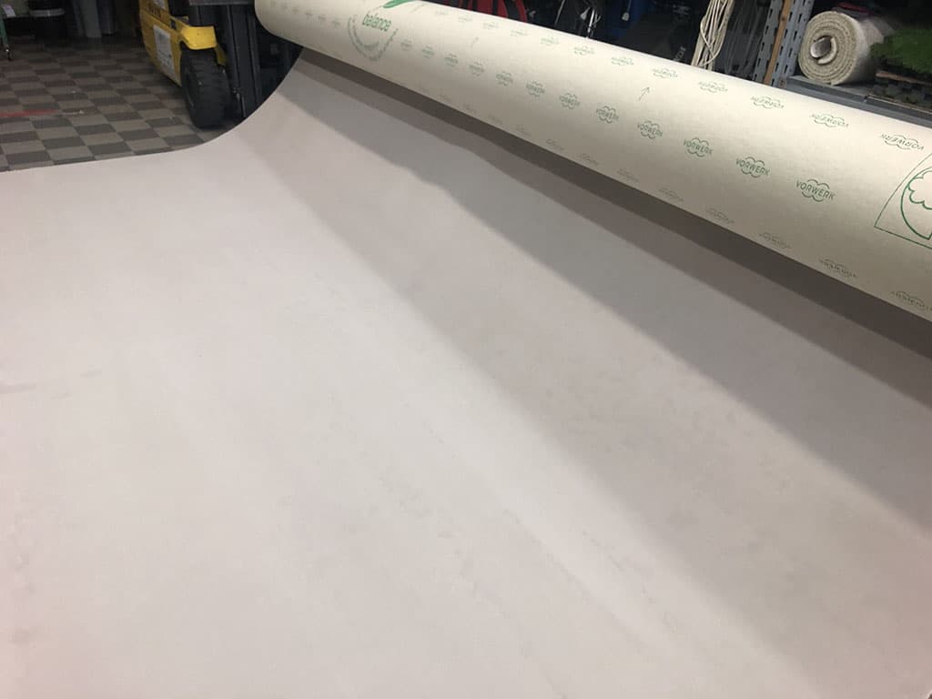 Rotolo di moquette tipologia Nertz carta o tessuto bianco su una macchina in un ambiente industriale o laboratorio di produzione.