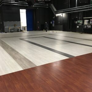 Palestra ampia con pavimentazione multicolore, luci soffuse e attrezzature disposte lungo le pareti.