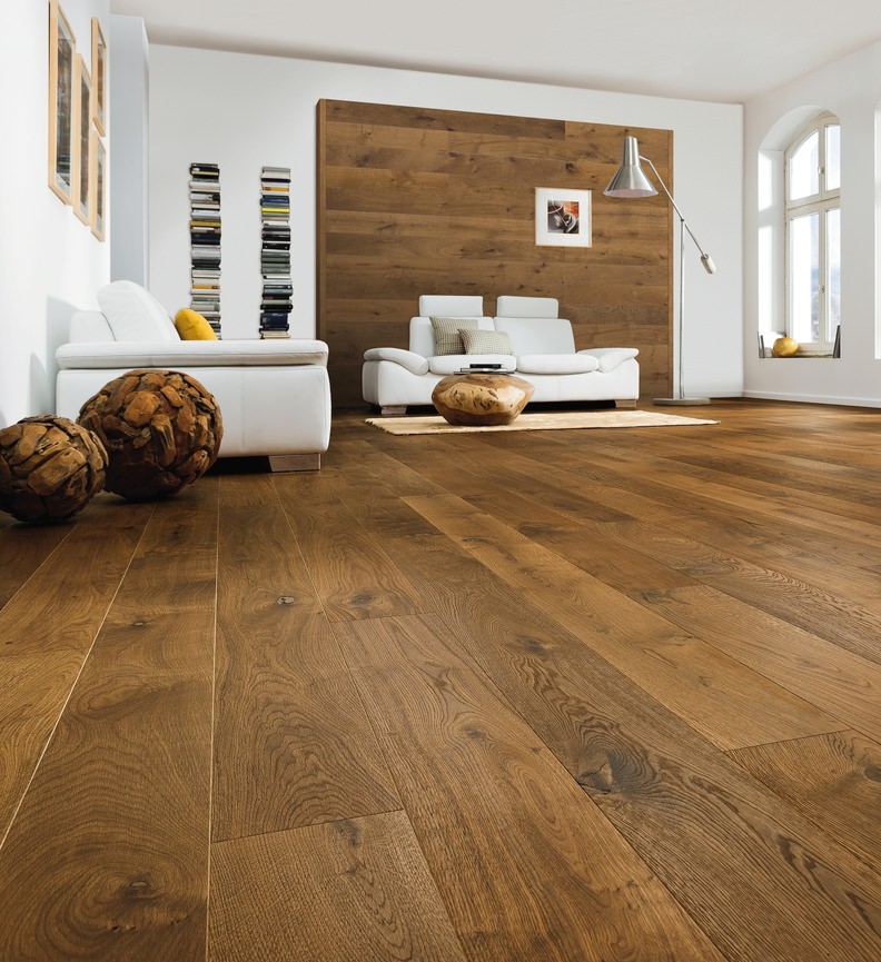 Elegante soggiorno minimale con pavimento in legno scuro, divano bianco e parete decorativa in legno.