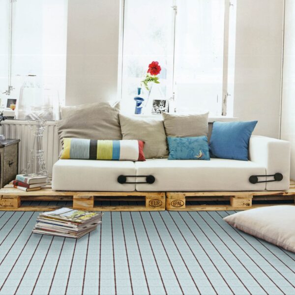 Un elegante salotto con un divano in pallet, cuscini colorati e un tappeto a righe, con luce naturale.