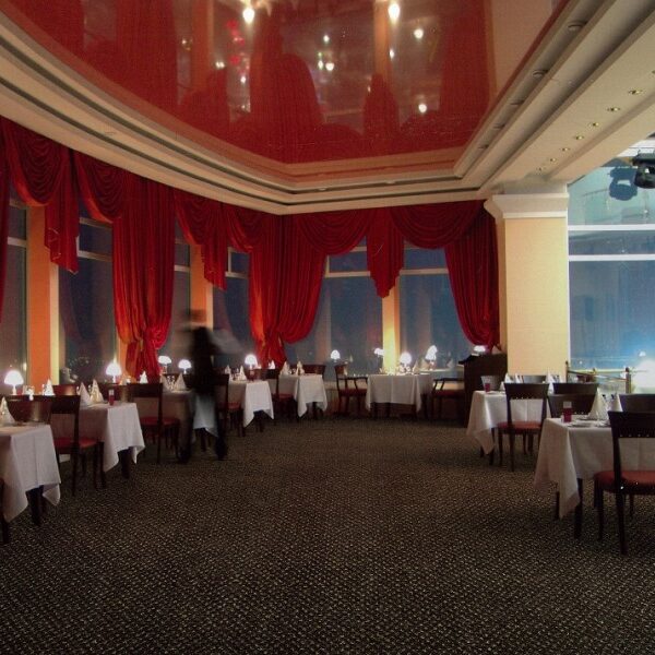 Elegante sala da pranzo con decorazioni in rosso e bianco, tavoli ben apparecchiati e illuminazione soffusa.