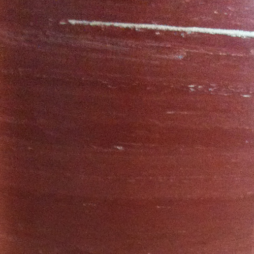 Immagine di un cilindro rosso con striature bianche. La superficie è liscia con sfumature di colore.