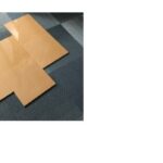 Pannelli di legno chiaro disposti in modo asimmetrico su un pavimento blu scuro, illuminati da luce naturale.