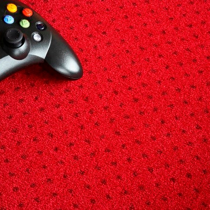 Controller nero e verde su un tappeto rosso con motivo di puntini neri. Concetto di gioco e intrattenimento.